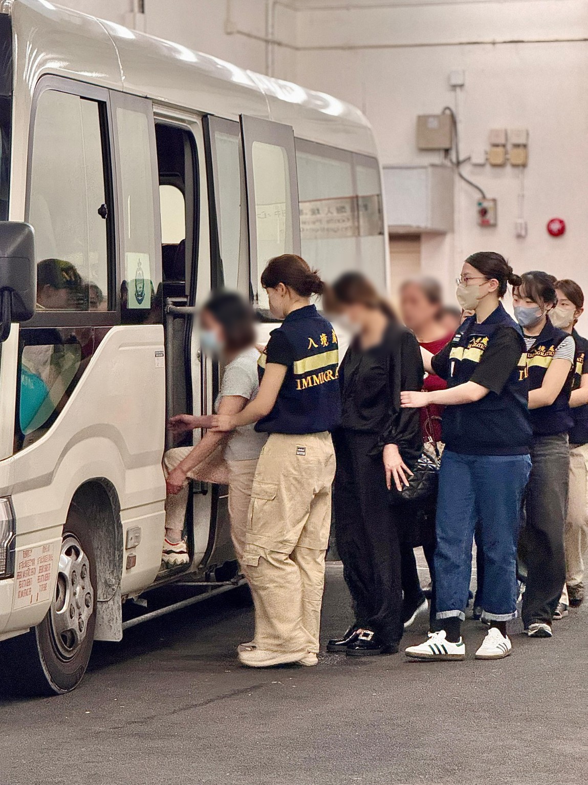 Photo shows removees being escorted by ImmD officers to proceed from the detention place to the airport