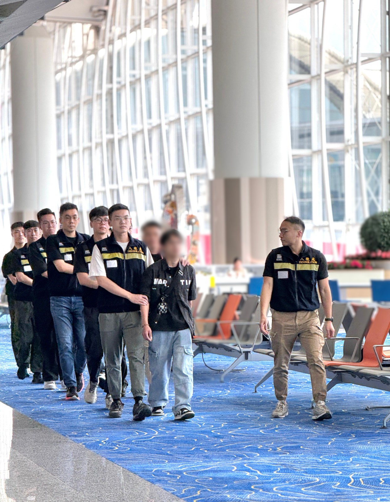 Photo shows removees being escorted by ImmD officers to depart from Hong Kong